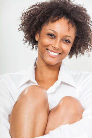 A beautiful happy mixed race African American girl or young woman wearing a white shirt smiling with perfect teethの写真素材