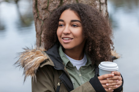Beautiful happy mixed race African American girl teenager female young woman smiling drinking...