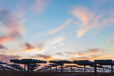 A field of photovoltaic solar panels providing alternative green energy at sunrise or sunsetの写真素材