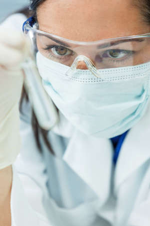 Female medical or scientific researcher or woman doctor looking at a test tube of clear solution in a laboratoryの写真素材