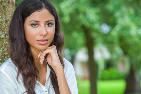 Outdoor portrait of a beautiful thoughtful young female Latina Hispanic womanの写真素材