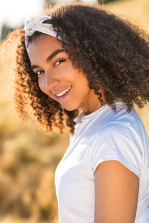 Outdoor portrait of beautiful happy mixed race African American girl teenager female child smiling with perfect teethの写真素材
