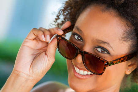 Beautiful young mixed race black African American woman smiling with perfect teeth and wearing sunglassesの写真素材
