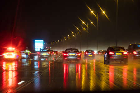 Motion blurred photograph of traffic at in night in the rain on a British motorway with police officer and carの写真素材