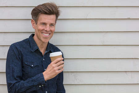 Portrait shot of an attractive, successful and happy middle aged man male outside drinking coffee in a disposable takeaway cup.の写真素材