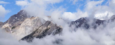 Panoramic aerial web banner photograph of clouds over snow covered Rocky Mountains in Canadaの写真素材