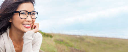 Web banner panoramic portrait of a beautiful chinese asian girl or young woman outside wearing glassesの写真素材