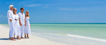 Panoramic web banner two couples, generations of a family together holding hands on a tropical beachの写真素材