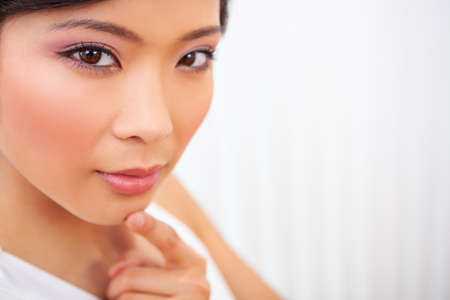 Close up portrait of a beautiful thoughtful Chinese Asian young woman or girl finger on chin thinkingの写真素材