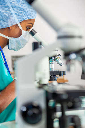 Asian female doctor or scientific researcher using her microscope in a medical research lab or laboratory.の写真素材