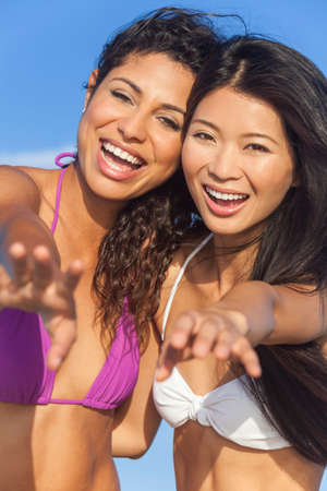 Beautiful young women girls in bikinis laughing having fun on a beachの写真素材