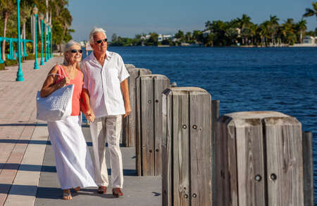 Happy senior man and woman romantic couple together looking out to tropical sea or river with bright clear blue skyの写真素材