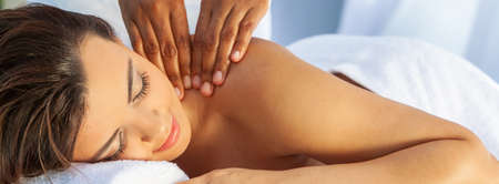 Panoramic web banner young woman relaxing outside at a health spa while having a massage panoramaの写真素材
