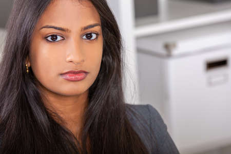 Portrait of a beautiful thoughtful young successful female Asian Indian business woman or businesswoman in officeの写真素材
