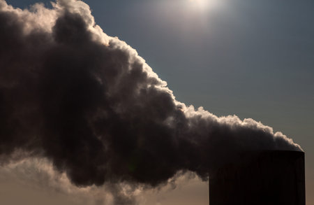 Pollution or smoke coming from the top of a chimney and blocking out the sun causing environmental...