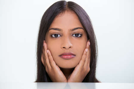 Studio portrait of a beautiful young Indian Asian woman or girl resting on her hand with white backgroundの写真素材