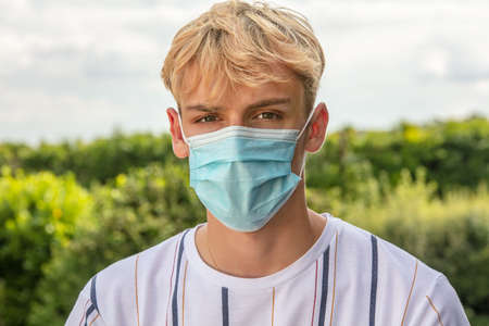 Boy teenager teen male young man wearing a face mask outside during the Coronavirus COVID-19 virus pandemicの写真素材