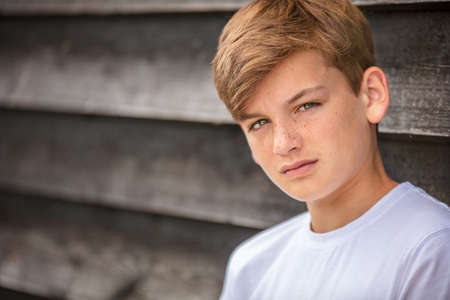 Portrait of a boy teenager teen male child wearing a white t-shirt outsideの写真素材