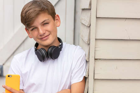 Boy teenager teen male child outside using his mobile cell phone and wireless headphones for social media or musicの写真素材