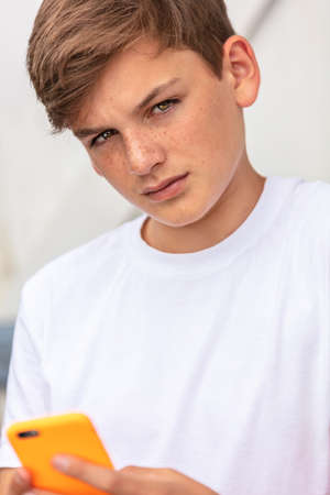 Boy teenager teen male child outside using his mobile cell phone and for social media or SMS text messagingの写真素材