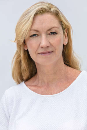 Studio portrait of an attractive middle aged blonde woman smiling on a white backgroundの写真素材