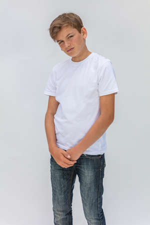 White background studio portrait of a boy teenager teen male child wearing a white t-shirt and blue jeansの写真素材