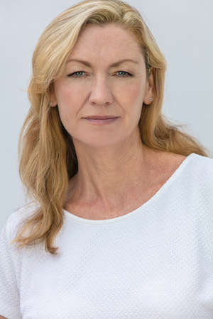 Studio portrait of an attractive middle aged blonde woman smiling on a white backgroundの写真素材