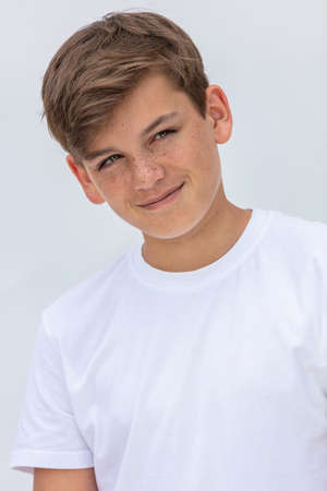 White background studio portrait of a smiling happy boy teenager teen male child wearing a white t-shirtの写真素材
