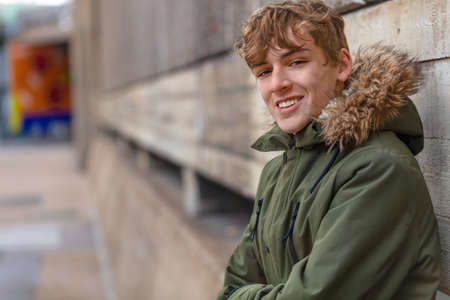 Male young adult teenager wearing a parka jacket outside and smilingの写真素材