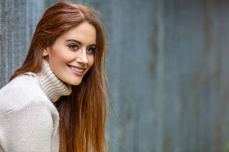 Outdoor portrait of beautiful girl or young woman with red hair smiling and happy in an urban city settingの写真素材