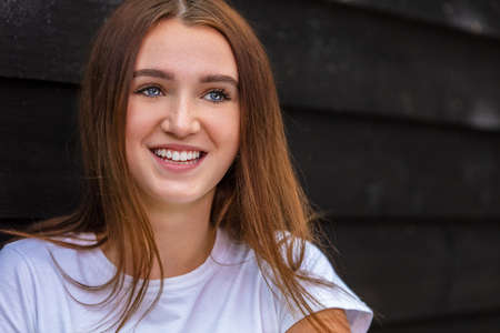 Beautiful happy smiling girl teenager female young woman with blue eyes and perfect teeth outside wearing a white t-shirtの写真素材