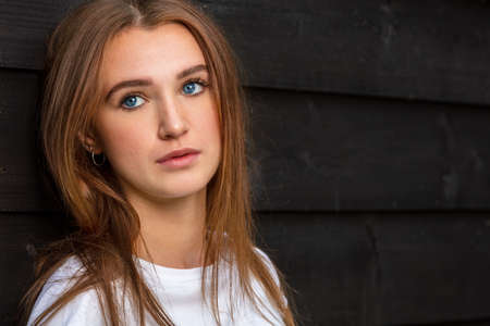 Sad depressed thoughtful girl teenager female young woman with blue eyes outside wearing a white t-shirtの写真素材