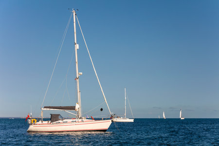 Sailboats or yachts sailing and at anchor on a blue sea in summer sunshineの写真素材