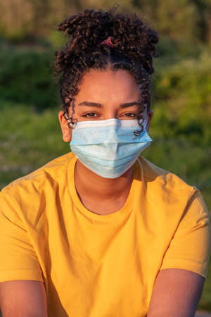 Mixed race African American teenager teen girl young woman wearing a face mask outside during the Coronavirus COVID-19 pandemicの写真素材