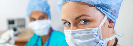 Panorama female medical or woman scientist weaing face mask using a microscope in a research lab or laboratory with her colleague panoramic web bannerの写真素材