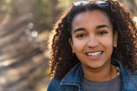 Outdoor portrait of beautiful happy mixed race African American girl teenager female young woman smiling with perfect teethの写真素材