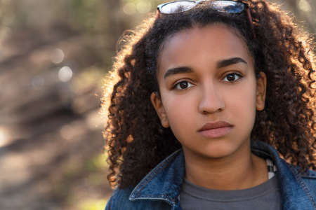 Outdoor portrait of beautiful happy mixed race African American girl teenager female child looking thoughtful or sadの写真素材