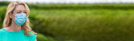 Panorama middle aged female woman wearing face mask outside in the  pandemic panoramic web bannerの写真素材