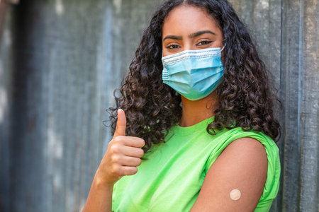 Vaccinated girl teenager teen mixed race biracial African American female young woman wearing face...