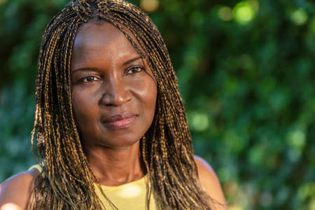 Outdoor portrait of attractive middle aged African or African American middle aged woman with braided hair in braidsの写真素材