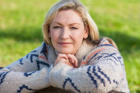 Attractive thoughtful middle aged woman leaning resting on fence in the countrysideの写真素材