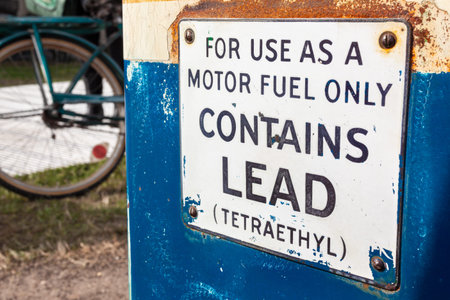 Old fashioned petrol, gas or gasoline fuel pump with lead and Tetraethyl warning sign and a bicycle...