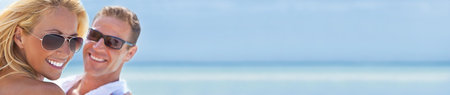 Panorama sexy and attractive man and woman couple smiling, happy wearing sunglasses in sunshine at the beach panoramic web banner headerの写真素材