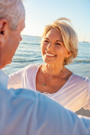 Happy senior man and woman old retired couple together on a beach with bright clear blue skyの写真素材