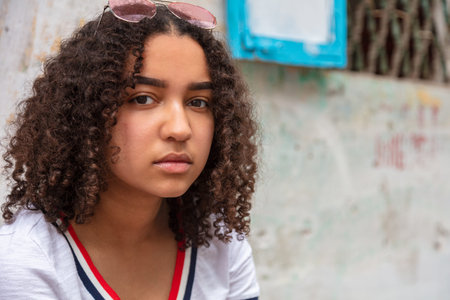 Outdoor portrait of beautiful thoughtful mixed race biracial African American girl female teenager with sunglassesの写真素材