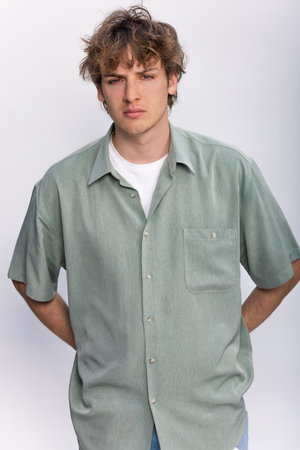 White background studio portrait of a handsome cool young man boy teenager teen young adult male wearing a white t-shirt and green shirtの写真素材