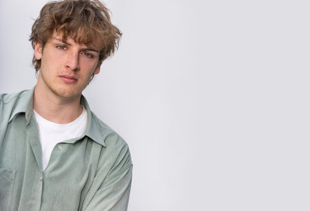 White background studio portrait of a handsome cool young man boy teenager teen young adult male wearing a white t-shirt and green shirtの写真素材