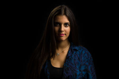 young brunette girl with long straight hair posing, black backgroundの写真素材