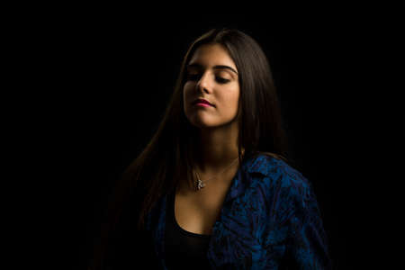 young brunette girl with long straight hair posing, black backgroundの写真素材