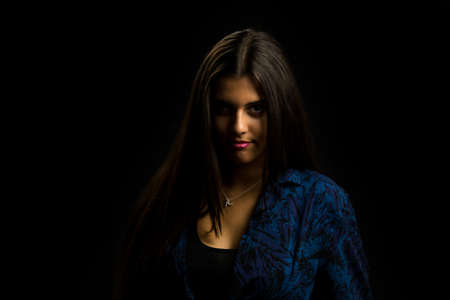 young brunette girl with long straight hair posing, black backgroundの写真素材